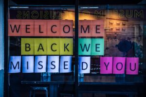 Vibrant sign reading 'Welcome Back We Missed You' displayed on a glass door.